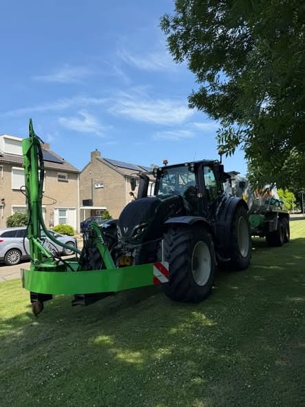 Tractor met watertank en gietarm geeft jonge straatbomen water